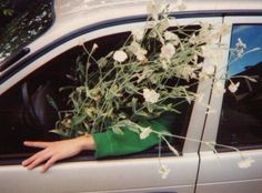 a person's hand sticking out the window of a car with flowers in it