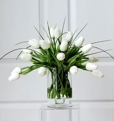 a vase filled with white tulips on top of a table