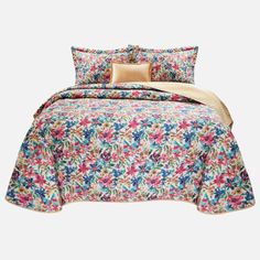 a bed covered in a colorful floral comforter and pillowcase with two pillows on top