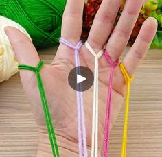 a person holding out their hand with four different colored string bracelets in front of them