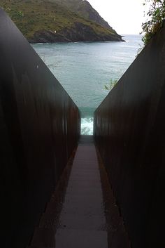 an open walkway leading to the ocean with hills in the background and water on either side