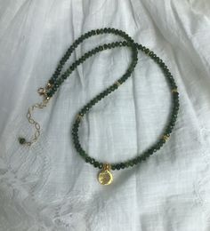 "This green gemstone beaded necklace has a gold vermeil tiny disc pendant with gold spacers. The chrome diopside faceted shiny beads are various shades of green. The gold vermeil disc pendant has a shiny finish. There are vermeil spacers, a gold filled lobster claw and 2\"extender chain. It measures 16' and is adjustable to up to 18'. Its great for layering with other necklaces." Gold Spiritual Emerald Necklace With Round Beads, Gold Emerald Necklace With Round Beads And Spiritual Style, Gold Crystal Necklace With Round Gemstone Pendant, Gold Emerald Necklace With Rondelle Gemstone Beads, Gold Emerald Necklace With Natural Stones And Round Beads, Gold Emerald Necklace With Natural Stones, Gold Emerald Necklace With Natural Round Beads, Gold Faceted Bead Crystal Necklace, Gold Jade Beaded Necklaces With Gemstone Beads