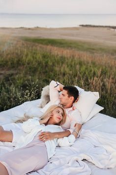 a man and woman laying on a bed in the grass