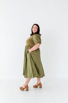 Features Mock neck Short puff sleeves with elastic Ribbed bodice Elastic waist Olive color Pockets 60% Cotton, 40% Polyester; Contrast: 52% Viscose, 26% Polyester, 22% Nylon Size + Fit Small 0-4, Medium 4-8, Large 8-12, X-Large 14-16, 1X 16-18, 2X 20-22, 3X 24-26 Kristin is 5'4", a size 1 and is wearing a Small Jaycie is 5'6" a size 18 and is wearing a 2X Runs true to size. Measurements taken while laying flat and then doubled. They do no account for stretch. Size Bra Band Length Small 34" 46" M Stretch Puff Sleeve Dress With Short Sleeves For Summer, Spring Dresses With Elastic Shoulders And Stretch, Spring Dresses With Stretch Elastic Shoulders, Casual Puff Sleeve Fitted Dress, Casual Fitted Puff Sleeve Dress With Elastic Sleeves, Green Puff Sleeve Dress With Elastic Sleeves, Fitted Green Midi Dress With Elastic Sleeves, Green Fitted Midi Dress With Elastic Sleeves, Solid Dress With Elastic Short Sleeves