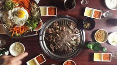 an overhead view of food and drinks on a wooden table with someone's finger pointing at it