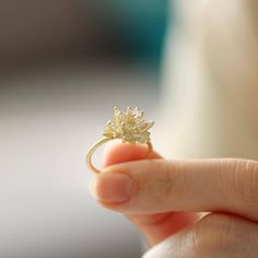 a person holding a ring with a flower on it's side in their hand