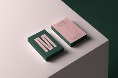 two green and pink business cards sitting on top of a white table next to each other