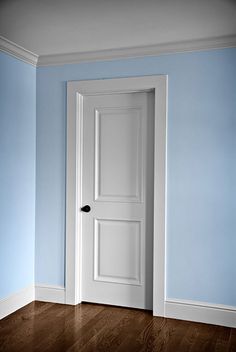 an empty room with a white door and blue walls