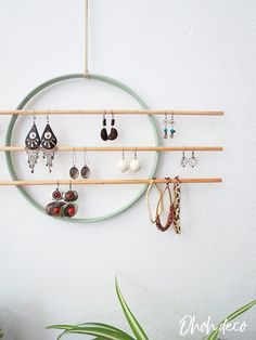 a circular rack with earrings hanging from it's sides and a plant in the background