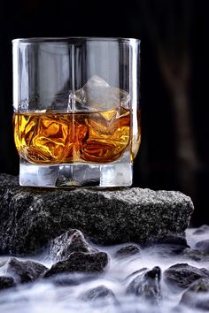 an ice cube sitting on top of a rock next to some water and rocks in front of it