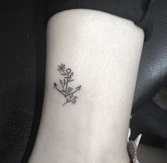 a small tattoo on the ankle of a woman's foot with an anchor and flowers