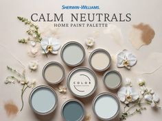 several cans of paint sitting on top of a table with white flowers and leaves around them