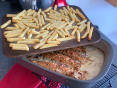 a pan filled with chicken and french fries on top of a red stovetop oven