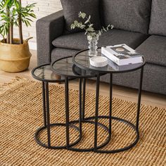 two glass tables sitting on top of a rug next to a couch