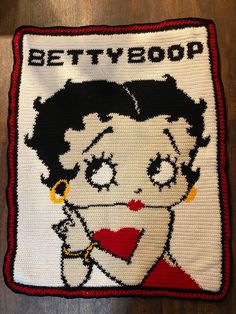 a crocheted bettyboom pillow on a wooden floor with an image of a woman's face