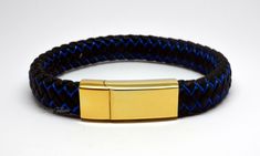 This stylish keepsake bracelet is made from 24k gold plated 316L non-tarnish stainless steel, with intricately braided black and blue leather straps.  As with all of our cremation/keepsake jewellery, it includes a discreet chamber in which to hold a small, token amount of ashes, fur, sacred earth or whatever you wish to hold close. All orders come complete with a presentation/gift box and a filling kit. The bracelet comes in 4 lengths:  Extra Small - 18cm/7.25inch long, to fit wrists up to 16cm Handmade Gold Leather Bangle Bracelet, Adjustable Engraved Gold Wristband, Adjustable Gold Engraved Wristband, Gold Engraved Wristband For Gift, Gold Wristband With Bracelet Strap As Gift, Elegant Gold Wristband As Gift, Elegant Gold Wristband For Gift, Elegant Blue Leather Bracelet For Gift, Gold Engraved Leather Bracelet Gift