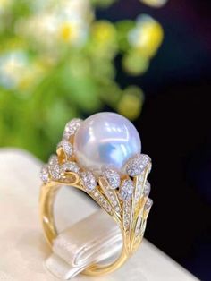 a pearl and diamond ring sitting on top of a white napkin with flowers in the background