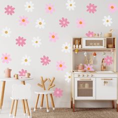 a child's play room with pink and yellow flowers on the wall, white furniture and wooden chairs