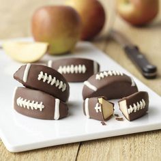 chocolate covered footballs on a white plate with apples in the background