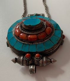 Tibetan Silver necklace with a big pendant deco with coral and turquoise ( i do not know how to open ). About prayer boxes: Traditionally, prayer boxes are used by Tibetans as portable shrines where prayers and sacred relics are kept. These prayer boxes marry that traditional concept with the Tibetan fascination for beautiful Jewelry. Tibetans write their wishes and prayers on a piece of paper and put it into the prayer box which they wear daily. By so doing, they believe that their godliness wi Traditional Oval Handmade Necklaces, Traditional Handmade Oval Necklace, Traditional Oval Handmade Necklace, Traditional Turquoise Necklace With Inlay For Gift, Traditional Turquoise Inlay Necklace As Gift, Bohemian Turquoise Inlay Necklace As Gift, Bohemian Turquoise Inlay Necklace Gift, Handmade Turquoise Medallion Necklace As Gift, Handmade Turquoise Medallion Necklace Gift