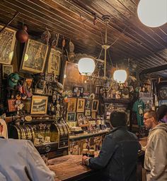 several people are standing at a bar with lots of items on the walls and ceiling