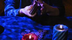 a person sitting at a table with some candles in front of them and one holding a cell phone