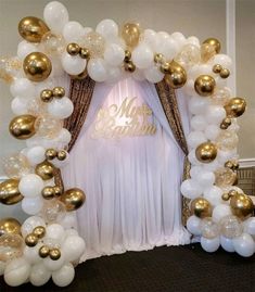 the balloon arch is decorated with gold and white balloons