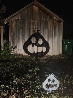 a black and white sign sitting in the grass next to a wooden shed at night