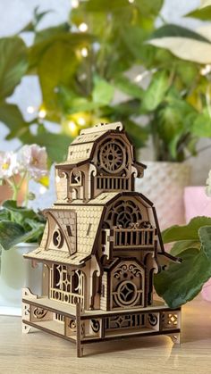 a small wooden house sitting on top of a table next to flowers and potted plants