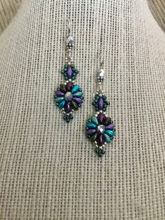 Pretty Peacock Multi colored Beaded Earrings... Super Duos in Matte Purple Lavender , Sage Green , and Ocean Blue , with Bali Silver Beads , Mirrored Silver Czech Crystal and Galvanized Blue and Silver Seed Beads ... measuring just shy of 2 inches on the ear with Sterling Silver ear wires and rubber ear nuts ... these are a fabulous , fun , delightful little earring . Purple Dangle Beaded Earrings With Spacer Beads, Elegant Purple Beaded Earrings With Colorful Beads, Superduo Earrings, Fantasy Crystal, Matte Purple, Weaving Ideas, Lavender Sage, Bead Projects, Peacock Color