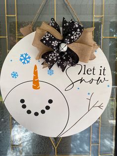 a snowman door hanger with a black and white bow