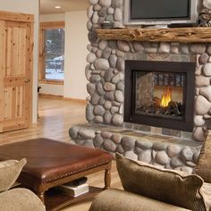 a living room with a stone fireplace and tv above the fire place in the center