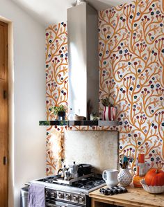 a stove top oven sitting inside of a kitchen next to a wall papered with flowers