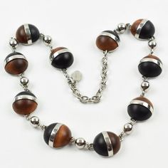 This is part of Chairish’s Costume Jewelry assortment.  Elegant modernist Balenciaga Paris signed necklace. It features a choker shape with a chromed metal chain ornate with geometric half-sphere cabochons in exotic woods. Signed with chrome metal tag at clasp: "BB - Balenciaga - Made in France". Spring-ring closing clasp with adjustable chain for length flexibility.  Measurements: necklace's total length is 19.69 in long (50 cm) - each cabochon element is 0.82 in diameter (2 cm).  Please see th Modern Round Cabochon Necklace, Elegant Brown Necklace With Polished Finish, Modern Silver Sphere Necklace, Modern Cabochon Necklace, Modernist Metal Necklace With Polished Finish, Elegant Necklaces With Wooden Beads, Elegant Wooden Beads Necklace, Modern Brown Round Jewelry, Unique Silver Jewelry With Wooden Beads