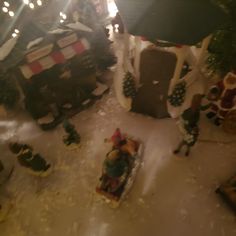 an aerial view of a christmas village with people and snowmen on the ground in front of trees