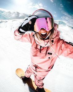 a woman riding a snowboard down a snow covered slope