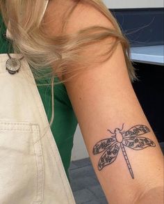 a woman with a dragonfly tattoo on her arm