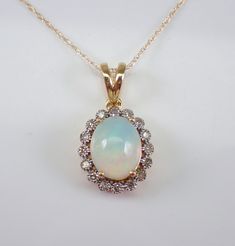 "Yellow Gold Diamond and Opal Pendant Necklace. The Necklace is set with one Oval Opal Cabochon in the center.  This Opal measures 10 X 8 mm and weighs 1 1/2 carats.  There are sixteen Round Brilliant Diamonds set in this pendant. These diamonds are H color, SI/I1 clarity and weigh a total of .25 carat.  The pendant is 10K Yellow Gold and comes with an 18\" 10K Yellow Gold chain and together weigh 2.5 grams.  The pendant measures 14 X 12 mm without the bail.  This necklace will be accompanied by Multi-stone Round Pendant Necklace For Anniversary, Classic White Jewelry With Gemstone Accents, White Gemstone Accent Necklace For Anniversary, Classic Round Multi-stone Necklaces, Classic Gemstone Accented Necklaces For Anniversary, White Necklace With Diamond Accents And Round Stone, White Necklace With Round Diamond Accents, Classic Gemstone Accents Necklaces For Anniversary, White Diamond Necklaces With Round Stone Accents