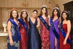 a group of women standing next to each other wearing dresses and tiaras on their heads