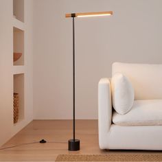 a white couch sitting next to a lamp on top of a wooden floor