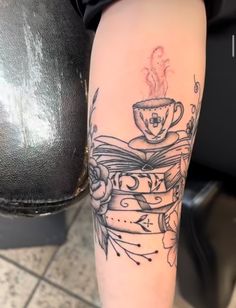 a woman with a tattoo on her arm holding a coffee cup and saucer in her hand