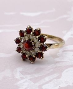 Vintage garnet and clear spinel 9ct gold ring, flower shape, raised setting. UK size N (US small 7). Hallmarked. Vintage Yellow Gold Flower Ring With Gemstone, Vintage Flower Ring With Gemstone, Vintage Flower Shaped Gemstone Ring, Vintage Garnet Ring With Center Stone, Vintage Garnet Birthstone Ring For Wedding, Vintage Gemstone Flower Ring For Anniversary, Vintage Formal Rings With Flower Shape, Vintage Round Garnet Cluster Ring, Victorian Hallmarked Flower Ring