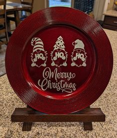 a red plate sitting on top of a counter next to a wooden stand with christmas decorations