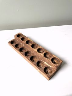 a wooden tray with holes in it sitting on a white counter top next to a wall