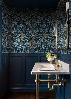 a bathroom with dark blue walls, gold fixtures and a marble sink in the corner