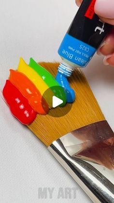 a person is painting the side of a paintbrush with different colored paints on it