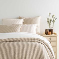 a bed with two planters on the nightstand and a white wall in the background