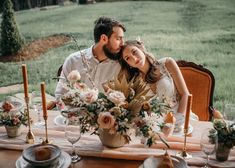 a man and woman sitting at a table with flowers