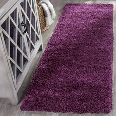 a purple rug is on the floor next to a white cabinet