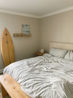 a bedroom with a surfboard on the wall and a bed in front of it